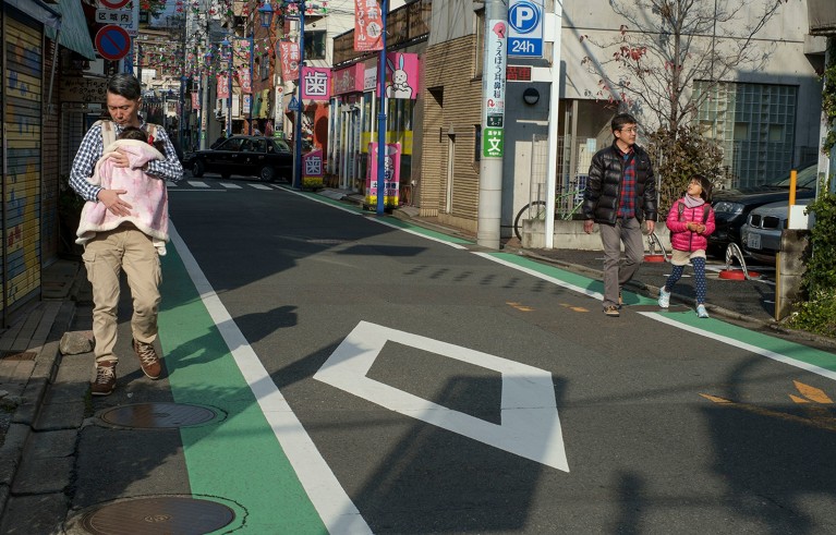 Father carrying a baby in a sling. Suburban street in the Seta District of Setagaya Ward, Tokyo.