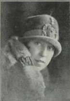 A young white woman wearing a felt hat low on her brow, and a fur collar.