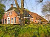 Grote boerderij met woonhuis met omlijste ingang en grote aan de voorzijde afgewolfde kap