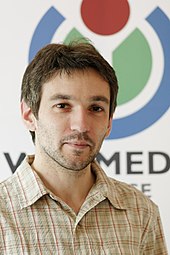 Mathis standing behind a Wikimedia France banner.