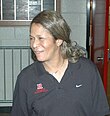 A woman looking to her right. She is wearing a grey polo inscribed with the Nike and Rutgers logos.