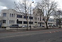 Long white building in winter, with trees in front