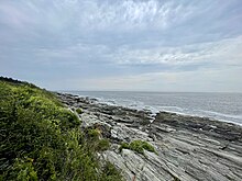 The rocky shoreline of Two Lights State Park with the open ocean beyond it.