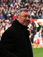 Alex Ferguson standing in front of a crowd of spectators