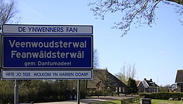 Plaatsnaambord in 2010, met de Nederlandse naam nog vermeld. Vertaald luidt de tekst De inwoners van Veenwoudsterwal heten u van harte welkom in hun dorp