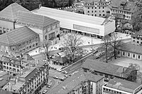 Moserbau 1 bis 3, Pfisterbau mit Bührlesaal und Restaurant, im Zentrum Heimplatz mit Tramwartehäuschen und Denkmal für Ignaz Heim, rechts alte, denkmalgeschützte Turnhallen, links unten Pfauenkomplex, 1963