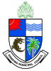 A quartered shield, blue and white. Top left has a red sun. Top right has blue waves. Bottom left has a crocodile. Bottom right has a coconut tree. Above, a green coat of arms of the Gambia. Below, a banner saying "KANIFING MUNICIPAL COUNCIL".