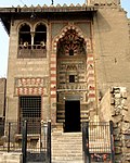 View of the entrance façade of the mosque/madrasa, with the sabil on the lower left and the kuttab on the upper left above it