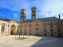 Bâtiment en pierre avec deux tours derrière.