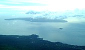 Photo showing large island (Kahoʻolawe) mostly covered by cloud, and the smaller islet of Molokini with the South Maui coast in the foreground