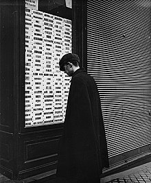 Photographié par Emil Mayer (de), homme observant des timbres-poste de collection proposés à la vente dans la vitrine d'un négociant spécialisé, à Vienne (Autriche), entre 1905 et 1914.