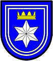 a double tressure—Azure; a facetted six pointed star [mullet] argent ensigned with a gable crown or, the whole within a double tressure argent—Langenhoven, RSA