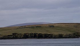 Extrémité Sud de l'île de Bigga avec les ruines d'une maison et les sommets de Mainland au dernier plan.