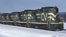 Four green and yellow locomotives pulling a train.