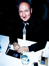 A smiling Stephen Jones, seated at a table