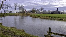 Het Damsterdiep gezien naar Winneweer met rechts de voormalige keukenfabriek met houten loodsen en een restant van de schoorsteenpijp