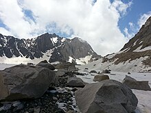 Piedras y guijarros descansando sobre un glaciar con las montañas al fondo.