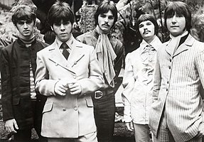 Black and white photo of five men in their late twenties with long hair.