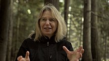 Portrait de Suzanne Simard avec une forêt en fond