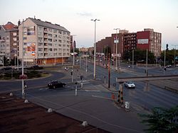 A kerületrész és a környék egyik központja, a Liget tér, alkonyatkor. A kép bal oldalán még Ligettelek, míg jobb oldalán már Óhegy látható