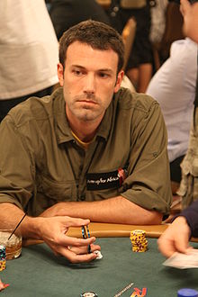 Serious looking young man throwing dice on a green felt gambling table.