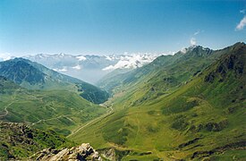 Photographie d'un col entouré de montagnes verdoyantes.