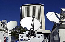 camiones de satélite aparcados en frente de un edificio grande