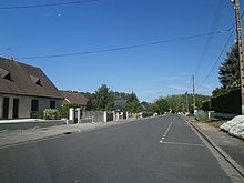 Photographie en couleurs d'un alignement de pavillons modernes de part et d'autre d'une route.