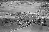 Gammelt flyfoto av Nøtterøy sentrum med det gamle kommunehuset fra 1923 på Tinghaug og Borgheim realskole fra 1950 (nå Borgheim ungdomsskole). Fylkesvei 308, som går over Nøtterøy mellom Tønsberg og Tjøme, er delvis skjult av bebyggelsen på bildet. Foto: Widerøe/Vestfoldmuseene