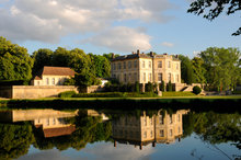 Vue au fond d'un château, se reflétant dans une pièce d'eau. An même niveau, sur la gauche, une batisse.