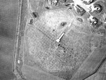 Image of a radar emplacement as seen from the air, in the center of a large mat formed of metal wire.