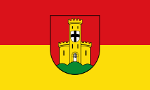 Blason en rouge et jaune avec un écu blanc orné d'une croix noire au milieu.