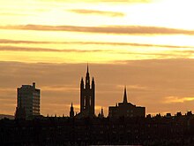 Grands bâtiments devant un ciel orangé.