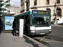 Bus vu de face, stationné près d'un arrêt. Le logo indique Roissybus et la destination affichée sur l'écran est Héropos - Roissy.le. Un symbole d'avion est aussi présent sur l'écran.