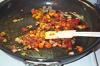 Brownish onions with carrots and celery in a frying pan.