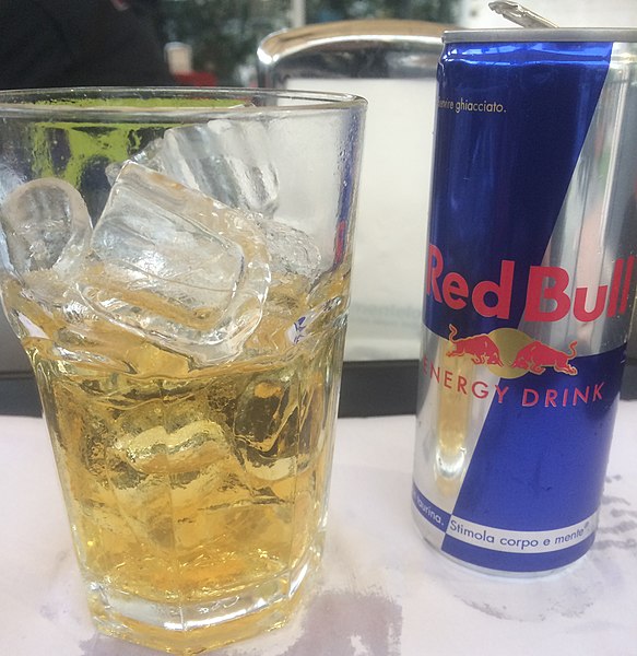 Напиток Red Bull в банке и в стакане со льдом