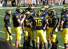 football team in yellow and blue uniforms in the huddle.