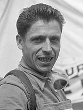 Photo en noir et blanc d'un homme souriant aux cheveux noirs.