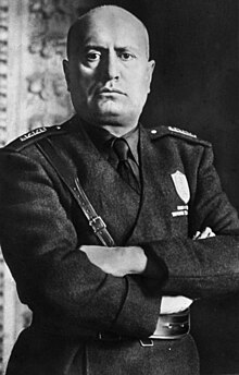 official portrait of Mussolini in uniform with crossed arms