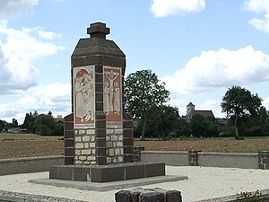 Le monument de la Vierge Marie. En arrière-plan à droite, l'église du village.