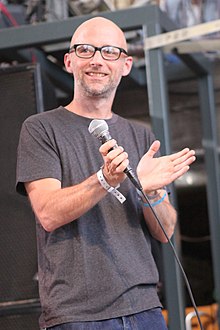 Moby holding a microphone and clapping