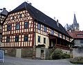 Fachwerkanwesen mit dem Turm der Pfarrkirche St. Sebastian