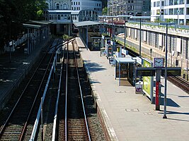 Der Bahnhof Hamburg-Blankenese * im Vordergrund Gleise und Bahnsteige, * links hinten das Empfangsgebäude mit den Treppenabgängen aus den 1980er Jahren, * rechts Neubauten auf dem ehemaligen Güterbahnhof