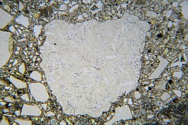 Hyaloklastit, Dünnschliff, Hellfeld: Glasbruchstücke in einer feinkörnigen Matrix; bei dem großen Bruchstück in der Bildmitte sind Kristallbildungen erkennbar.