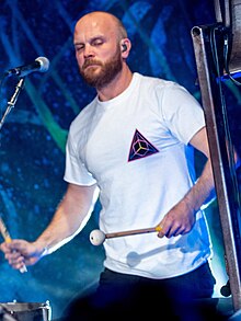 Champion on stage with his bell and timpani, wearing a white shirt