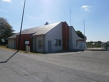 Photographie en couleurs d'un bâtiment récent avec garages partiellement peints en rouge