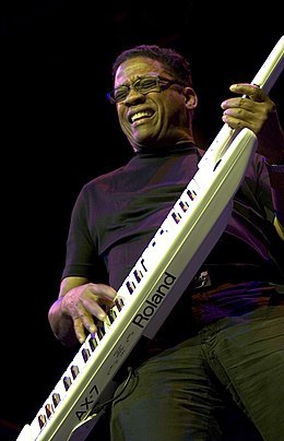 Homme en train de jouer du keytar sur scène.