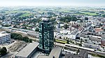 Luftbild auf eine Siedlung herunter mit einem Hochhaus im Zentrum des Bildes. Das umgebende Land ist flach.