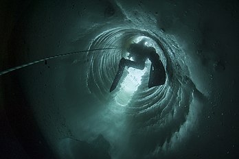 Un plongeur scientifique polaire s'engouffrant dans un tube foré dans la glace, à la base antarctique Dumont-d'Urville, sur l'île des Pétrels, en terre Adélie. (définition réelle 4 256 × 2 832)