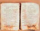 A photograph of two pages of a book written in a Greek script. The lower portions of both pages are damaged.